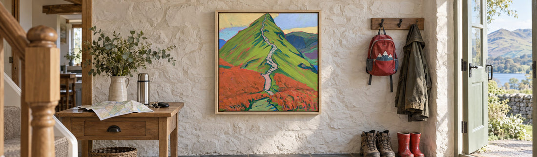 A framed canvas of the path up Cat Bells in a holiday cottage hallway, with a walking map, walking boots and a child's red wellies