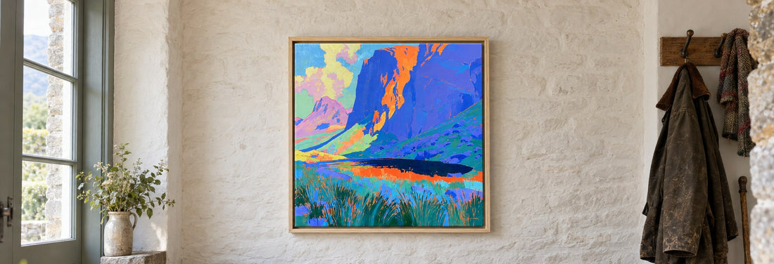 A framed canvas of Stickle Tarn beneath Pavey Ark, hanging above an oak bench with walking boots and a rucksack in a farmhouse boot room