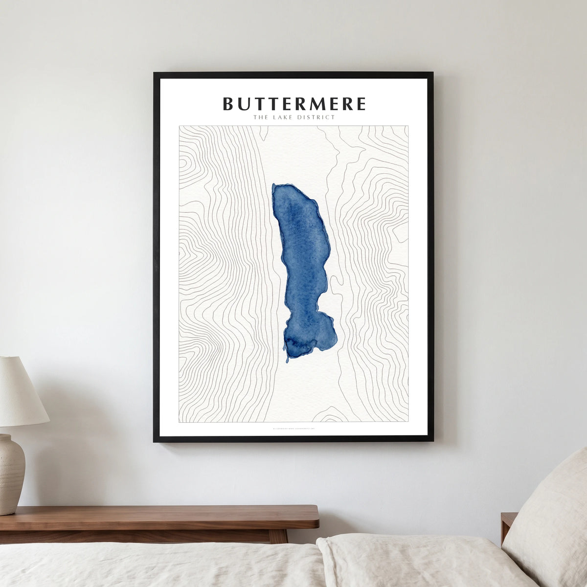 Buttermere lake map poster in a black frame, hanging in a bedroom