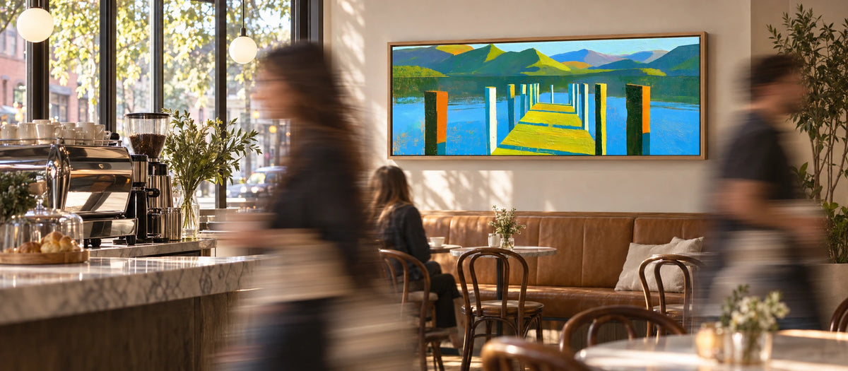 People passing in motion blur while a wide Lake District panorama stays sharp on the wall