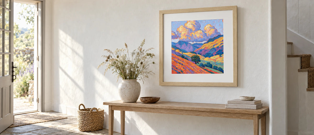 Golden Fellside with Violet Shadows — 70cm natural-wood framed print above a console table in a whitewashed cottage hallway