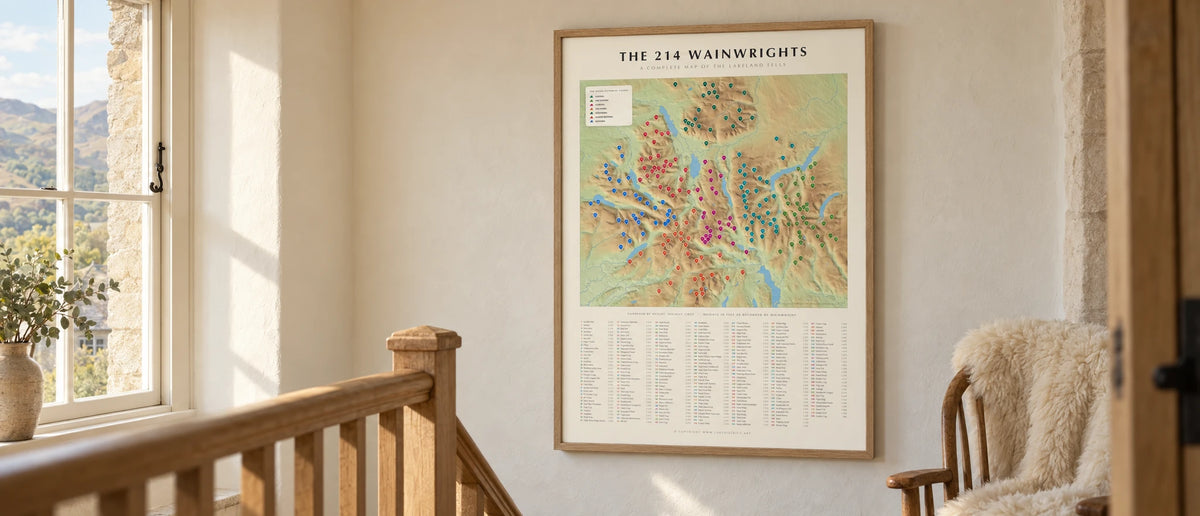 The 214 Wainwrights terrain map poster in a natural oak frame on a cottage staircase landing